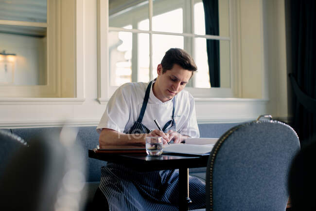 Giovane chef di sesso maschile scrivendo menu nel ristorante — Foto stock