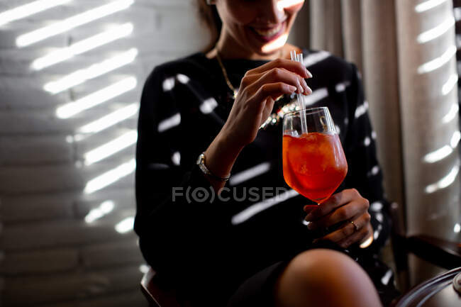 Cropped shot of happy young woman drinking spritz cocktail in boutique hotel restaurant, Italy — Stock Photo