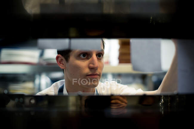Joven chef masculino leyendo pedidos de comida en la cocina - foto de stock
