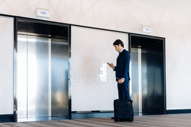Empresário com bagagem de rodas por elevador do hotel — Fotografia de Stock