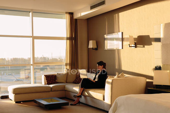 Mulher de negócios usando laptop na área de estar do quarto do hotel — Fotografia de Stock