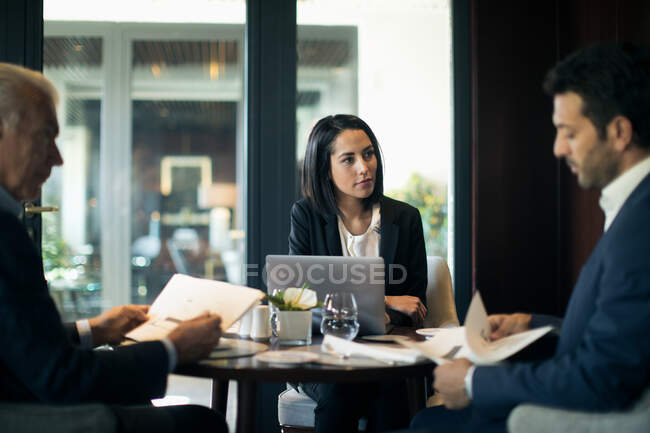 Mujer de negocios y hombres que tienen reunión en el restaurante del hotel - foto de stock