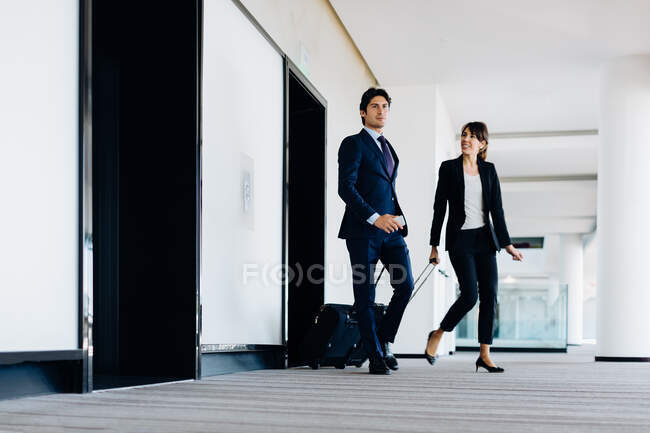 Homme d'affaires et femme d'affaires avec bagages à roues dans le bâtiment de l'hôtel — Photo de stock