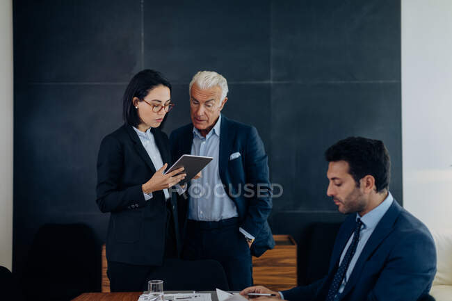 Uomo e donna d'affari che guardano tablet digitale in sala riunioni — Foto stock