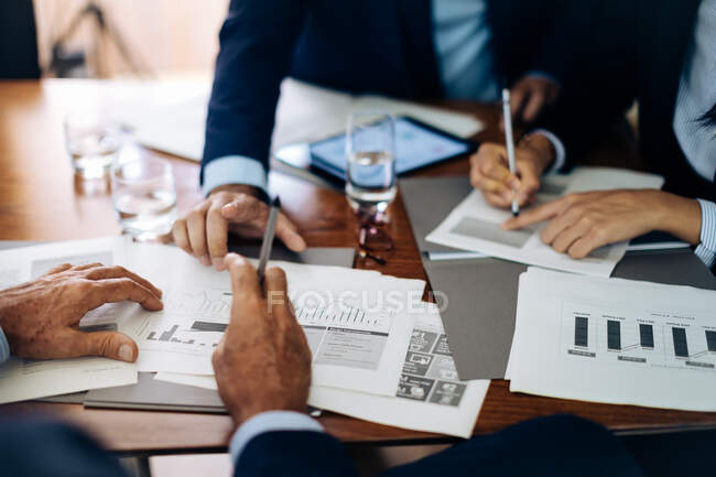 Businessmen and woman at boardroom table working on paperwork, cropped — Stock Photo