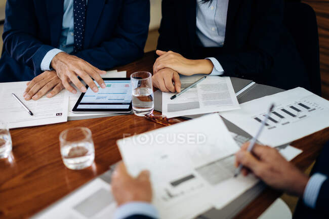 Empresários e mulher na mesa da diretoria usando tablet digital e trabalhando em papelada, cortada — Fotografia de Stock