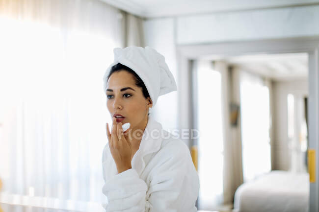 Donna che applica balsamo labbra in suite — Foto stock