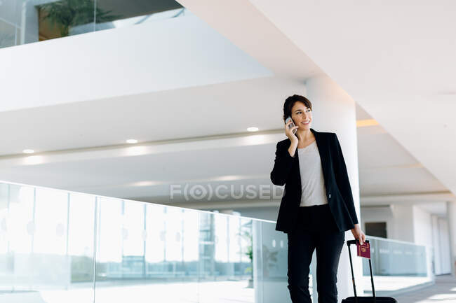 Businesswoman with wheeled luggage in hotel building — Stock Photo