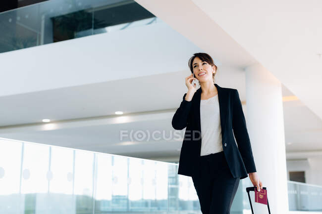 Businesswoman with wheeled luggage in hotel building — Stock Photo