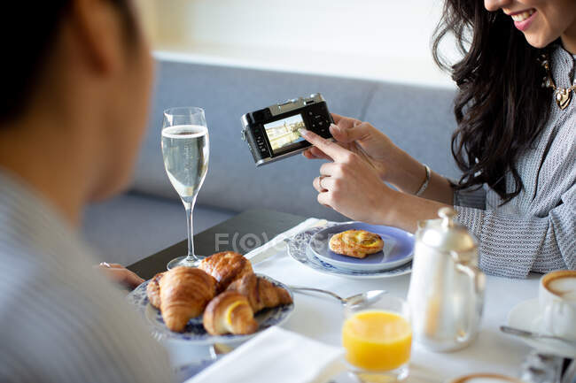 Junge Frau zeigt auf Digitalkamera beim Champagnerfrühstück im Boutique-Hotel in Italien — Stockfoto