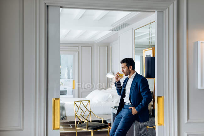 Uomo d'affari con bevanda ghiacciata, immerso nei pensieri nella suite — Foto stock