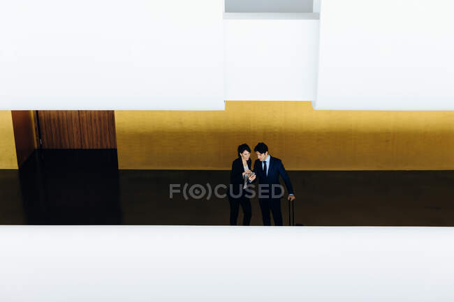 Geschäftsmann und Geschäftsfrau mit Rollgepäck im Hotelgebäude — Stockfoto