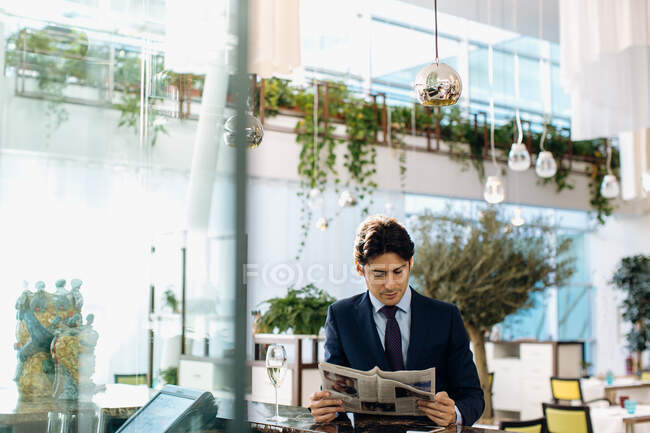 Бизнесмен, читающий газеты, выпивая в баре — стоковое фото