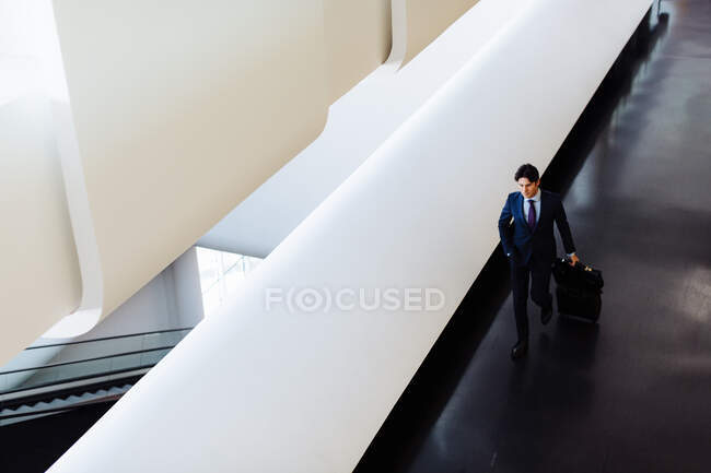Businessman with wheeled luggage in hotel building — Stock Photo