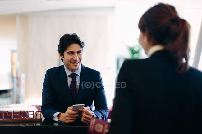Empresario registrándose en la recepción del hotel - foto de stock