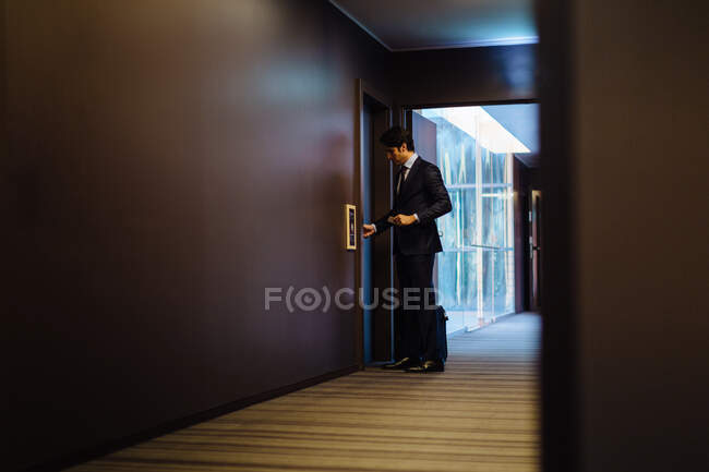 Homme d'affaires avec bagages à roues entrant dans la chambre d'hôtel — Photo de stock