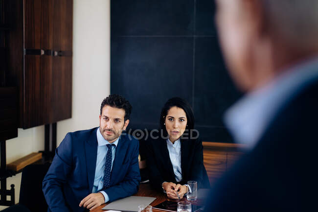 Businessman and woman watching presentation, over shoulder view — Stock Photo