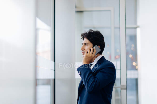Бизнесмен использует смартфон в офисном здании — стоковое фото