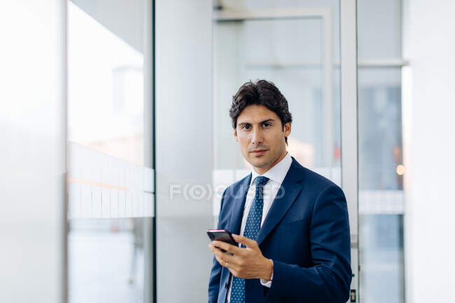 Бізнесмен використовує смартфон в офісному будівництві — стокове фото