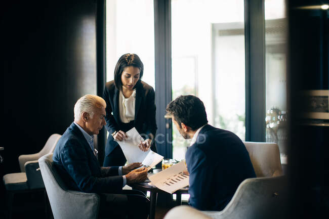 Businesswoman and men having meeting in hotel restaurant — Stock Photo