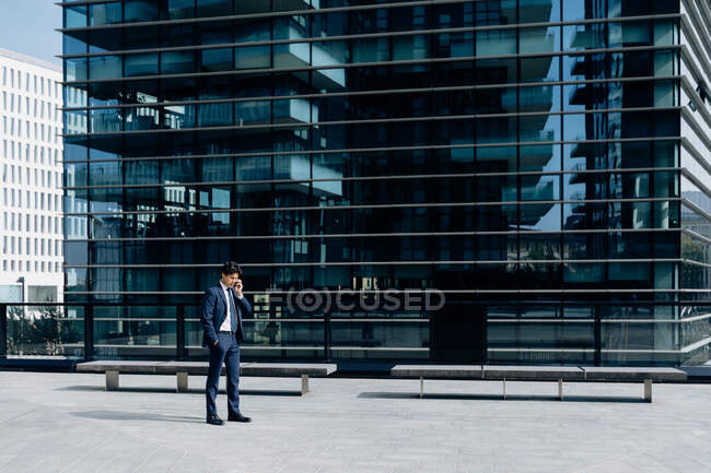Бізнесмен використовує смартфон перед офісною будівлею — стокове фото