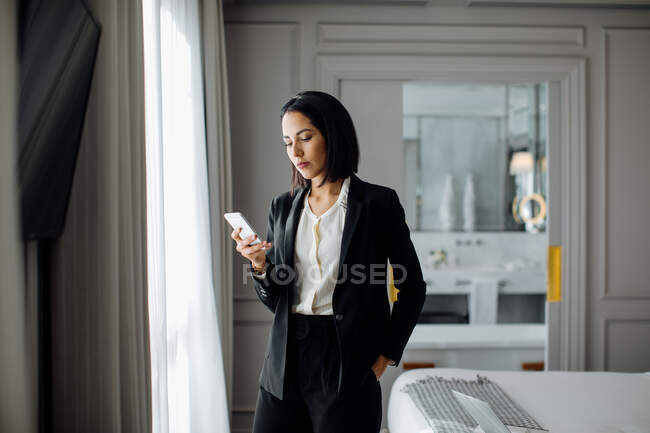 Donna d'affari utilizzando smartphone in suite — Foto stock