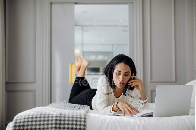 Femme d'affaires utilisant smartphone et ordinateur portable en suite — Photo de stock