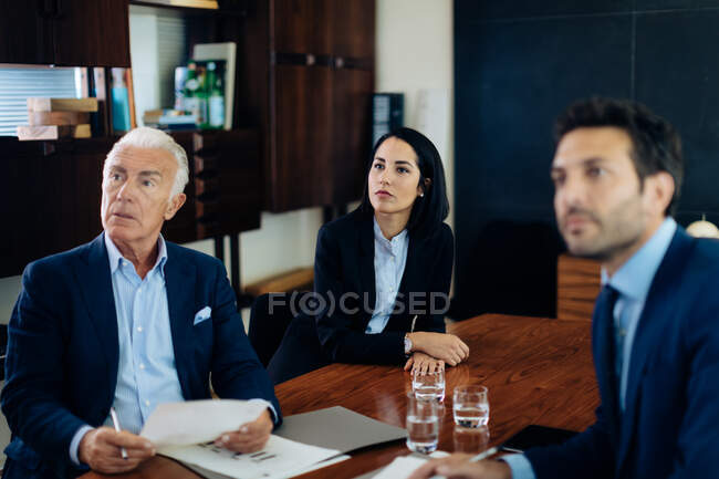 Businessmen and woman watching presentation from boardroom table — Stock Photo