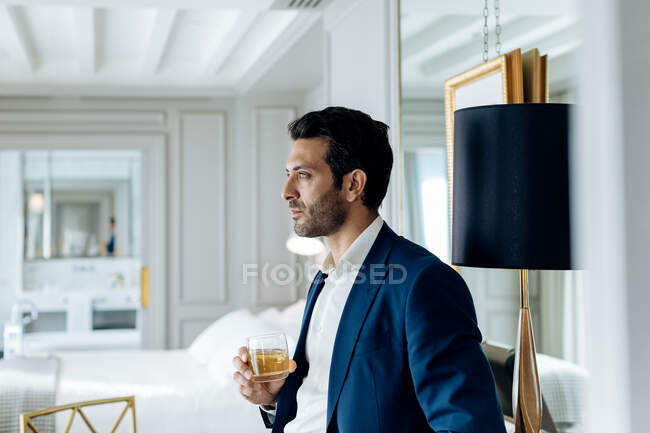 Empresário com bebida gelada, profundamente em pensamentos em suite — Fotografia de Stock