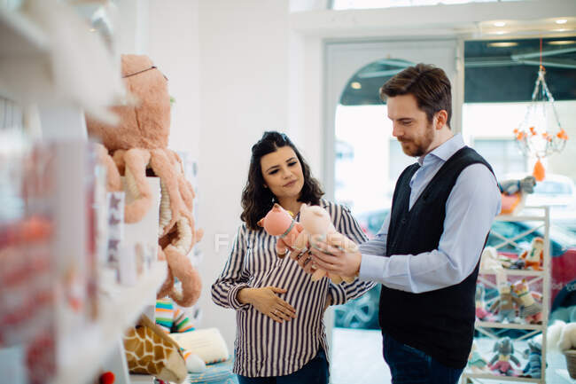 Муж и беременная жена покупают мягкие игрушки — стоковое фото