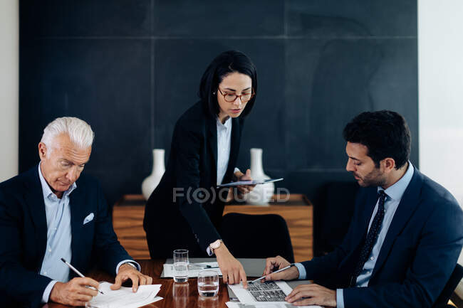 Бізнесмени і жінка, дивлячись на графіки і папери за столом на дошці — стокове фото