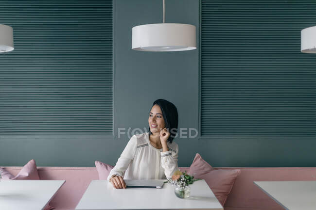 Молода бізнес-леді за готельним столом, дивлячись далеко — стокове фото