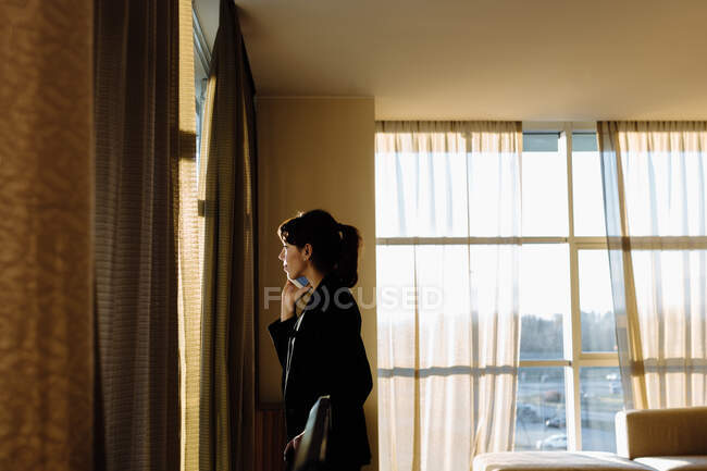 Donna d'affari che utilizza il telefono cellulare dalla finestra — Foto stock