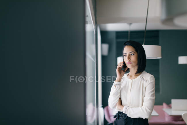 Young businesswoman in hotel making smartphone call — Stock Photo