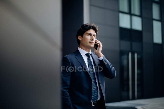 Homme d'affaires utilisant un smartphone devant un immeuble de bureaux — Photo de stock