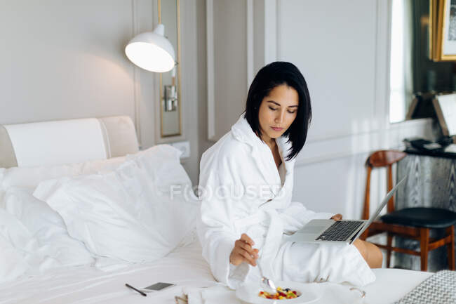 Donna che utilizza il computer portatile e fare colazione in suite — Foto stock