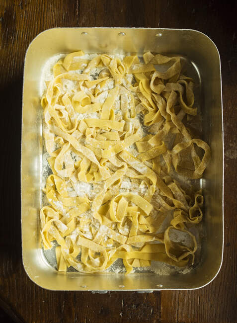 High angle close up of freshly made Tagliatelle pasta in a metal tray. — Stock Photo