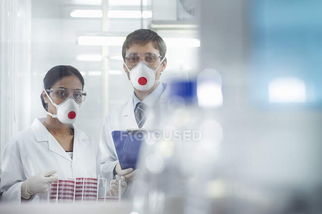 Ученые в изолированной среде в масках, работающие в исследовательской лаборатории. — стоковое фото