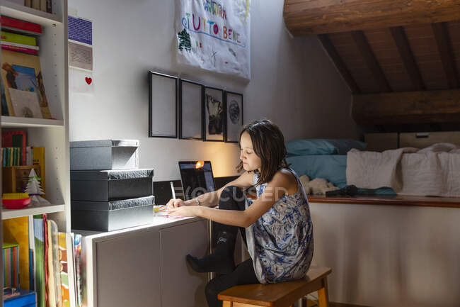 Mädchen sitzt in ihrem Schlafzimmer und macht Hausaufgaben während Coronavirus Lockdown. — Stockfoto