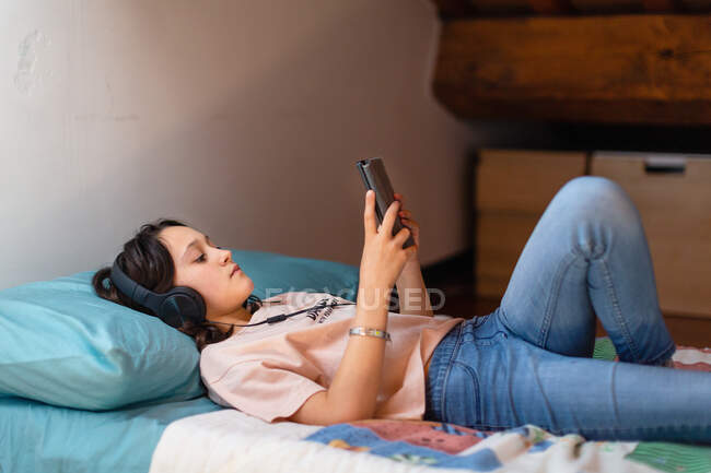 Дівчинка лежить на ліжку, слухаючи музику під час блокування Coronavirus. — стокове фото