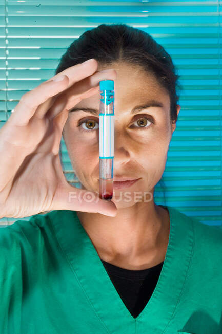 Close up of female doctor holding test tube with red liquid. — Stock Photo