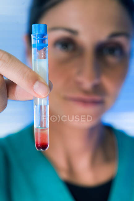 Primo piano del medico femminile che tiene la provetta con liquido rosso. — Foto stock