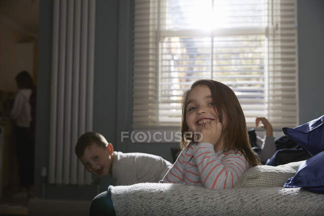 Двоє дітей сидять на дивані в піжамі, посміхаючись на камеру . — стокове фото