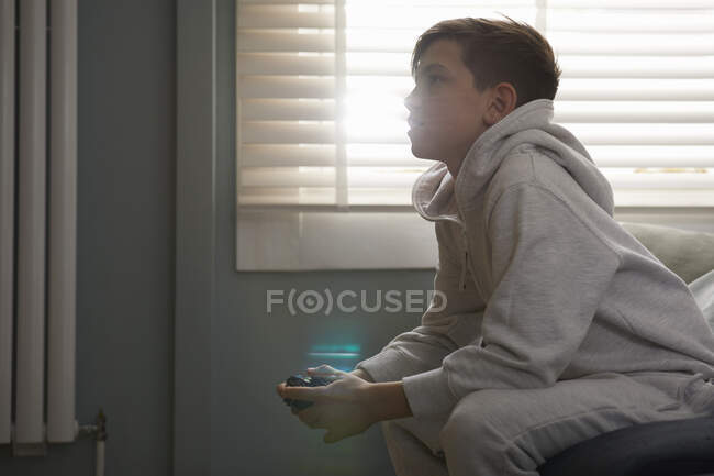 Мальчик сидит на диване в пижаме, смотрит телевизор. — стоковое фото
