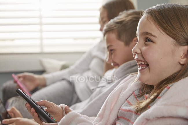 Група дітей сидить на дивані в піжамі, дивиться телевізор . — стокове фото