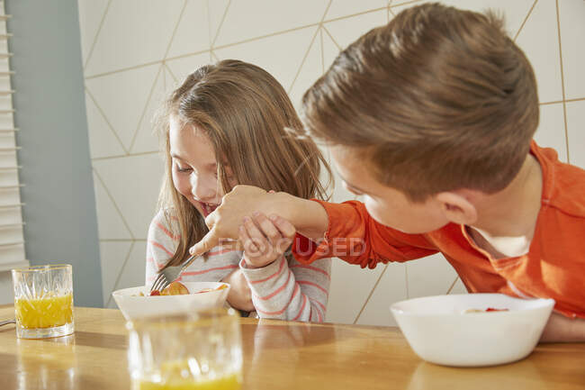 Boy and girl sitting at kitchen table, eating breakfast. — Stock Photo