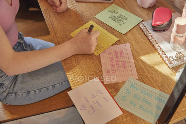 Вид сверху девушки, пишущей заметки на цветной бумаге — стоковое фото