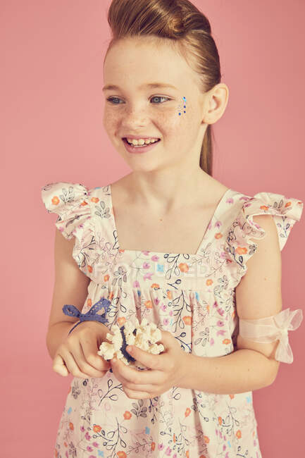 Портрет усміхненої дівчини брюнетки в сукні з квітковим візерунком на рожевому фоні — стокове фото