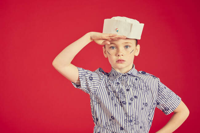 Bonito morena menina vestindo marinheiro chapéu e posando, olhando para a câmera com a mão na cabeça — Fotografia de Stock