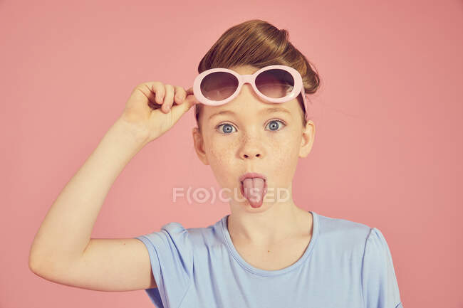 Portrait de fille brune sur fond rose, sortant la langue à la caméra — Photo de stock